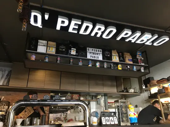 Inside the cafe, the shop name is posted up on the ceiling in big block letters, right above the espresso bar and hanging shelves. Cabinets line the back wall.