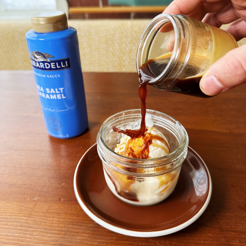 Cabell's drink. Espresso is being poured from a glass jar onto a scoop of ice cream and sea salt caramel sauce in another jar.