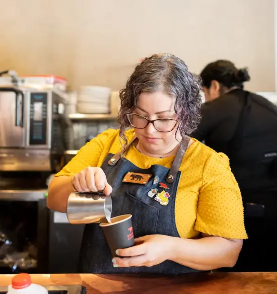 Devorah pours a latte behind the bar at Equator.