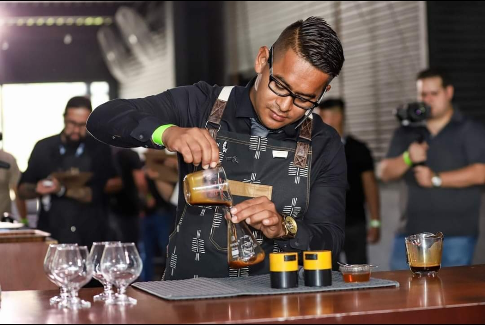 Carlos Cubias pours coffee into a glass to create a signature drink at a barista competition.