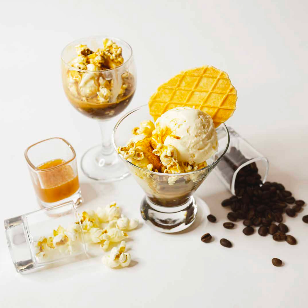 Piyapet "Flook" Lapteerawut's submission for the Ghirardelli Cool Caramel Challenge is the Caramel Popcorn Affogato. There is ice cream and popcorn in a glass with caramel sauce. Ingredients for the drink are artfully scattered around the glass.