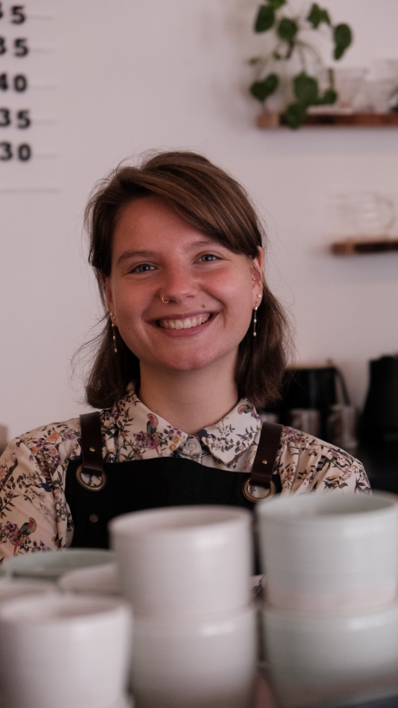 Ella Simon posing behind a stack of ceramic cups.