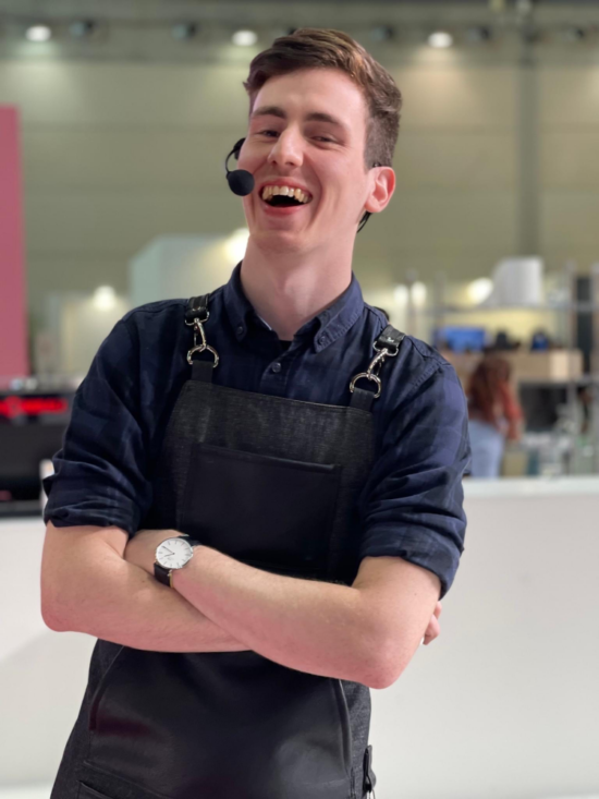 Daniele Ricci smiles as he poses with his arms crossed at a barista competition.