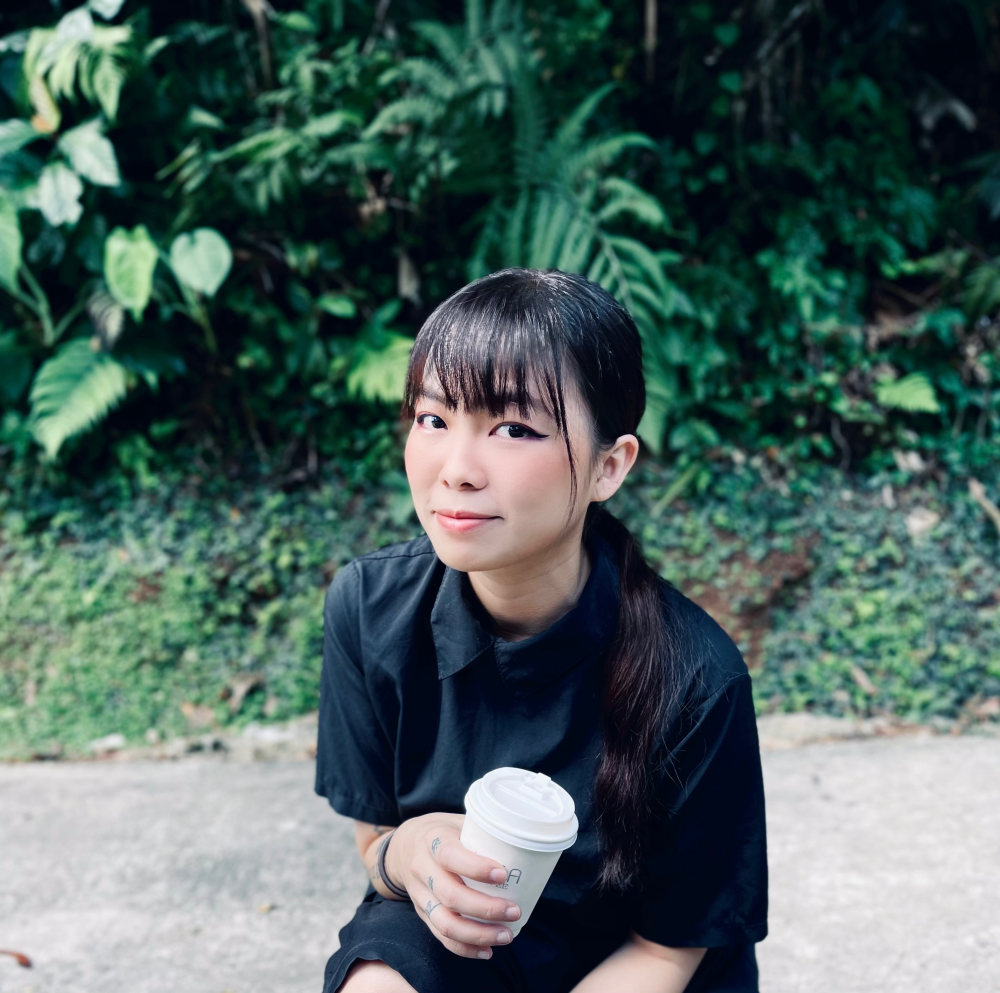 Rain Lee holds a to-go coffee cup and poses for the camera.