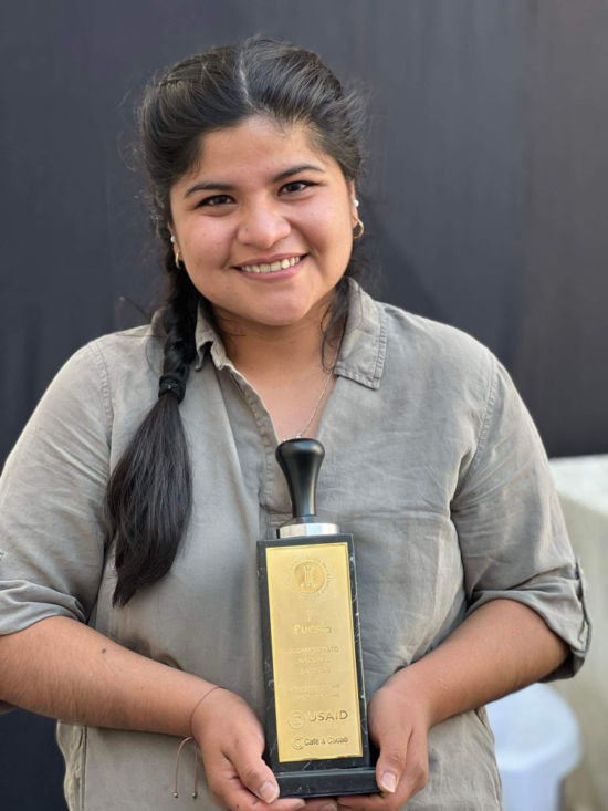 Jhosseline Benites holds her first place trophy and smiles at the camera.