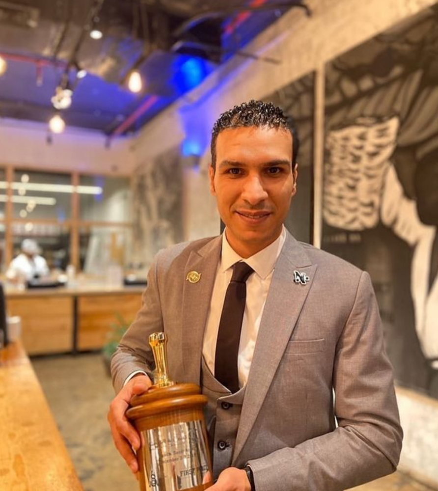 Ahmed Abdelaziz holds his first place trophy and smiles for the camera as he advances to the World Barista Championship.