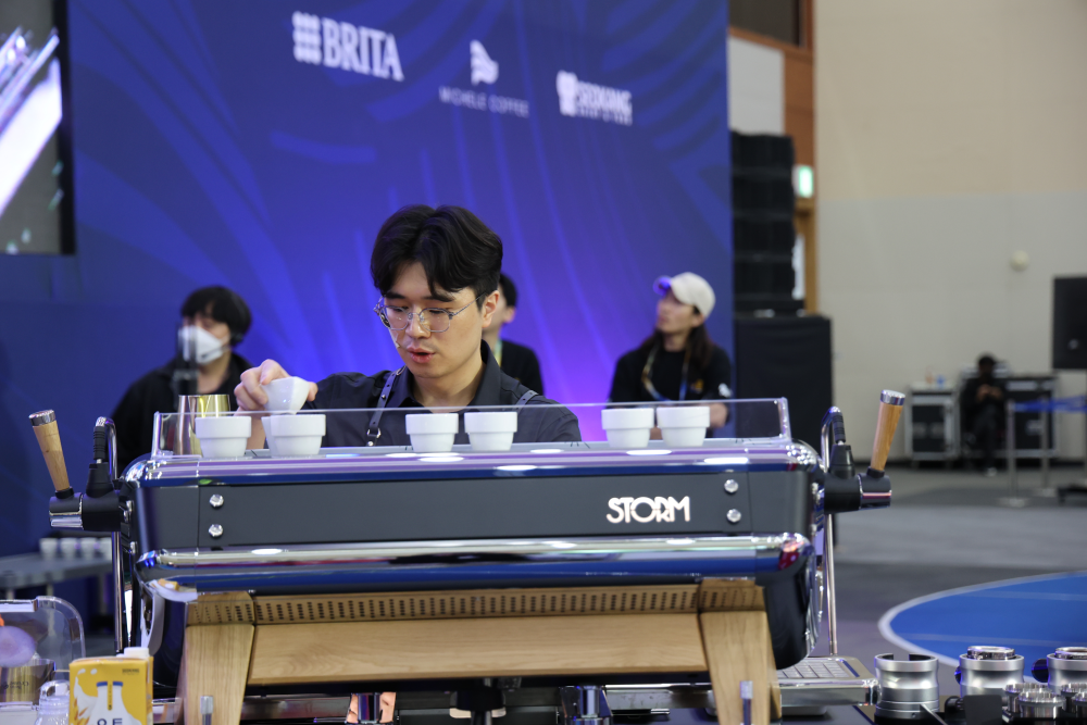 South Korean barista champion Donghwan Dong prepares espresso behind a machine during a barista competition.