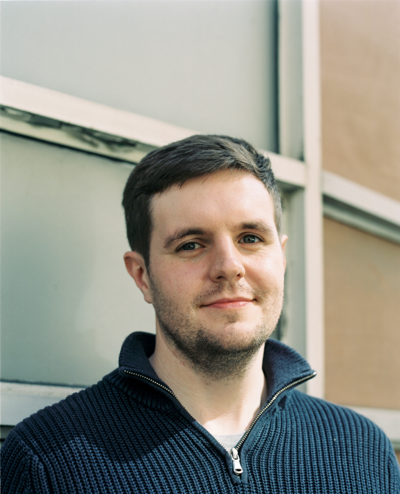 Ian Kissick wears a blue knit pullover and smiles a the camera.