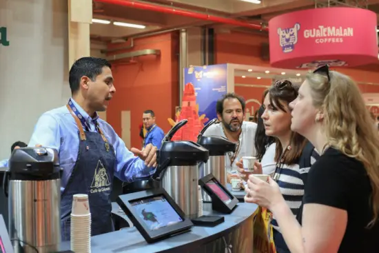 A man describes coffee to people at his counter while the try it.