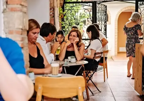 Women sit at a table in a busy cafe.