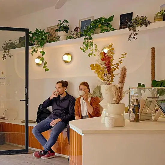 A couple sits and sips coffee on a bench inside Fran Cafe.