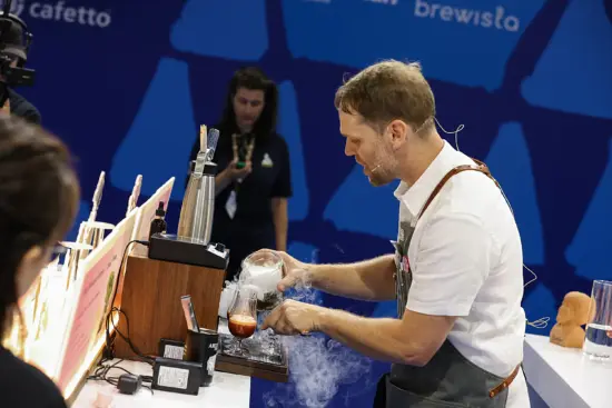 Isaiah pours a misty liquid into cups for his drink prep.