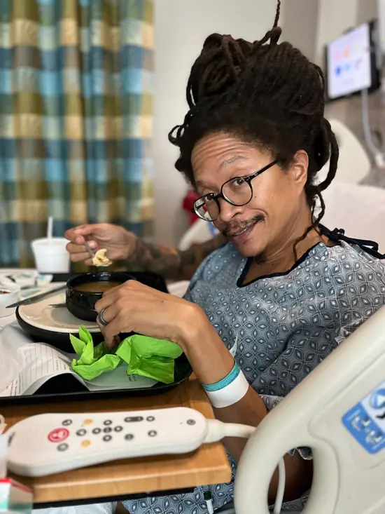 Lem eats dinner from a hospital bed.