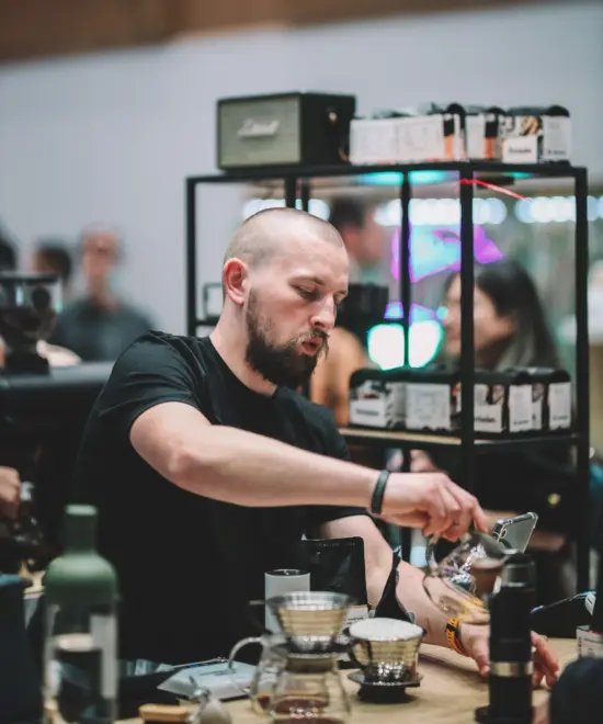 A barista prepares coffee for pourover in a competition.