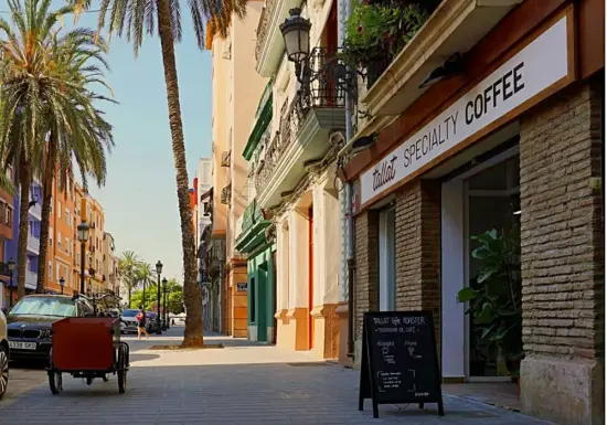 Tallat's storefront in Valencia, with palm trees growing outside and a blackboard sign on the sidewalk. 