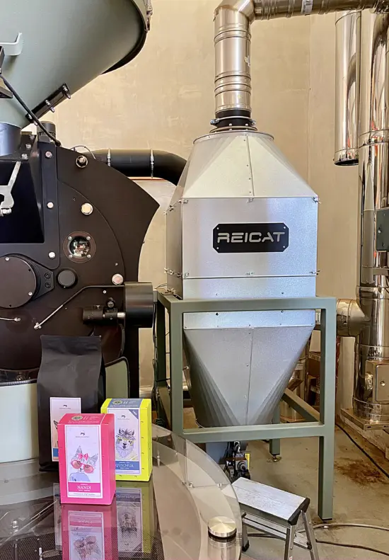 A ReiCat air purifier attached to a roaster. It resembles a metal potbelly stove with a long stovepipe up top.