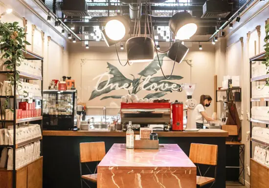 A view of inside a One Love coffee shop, with masked barista working in a corner.