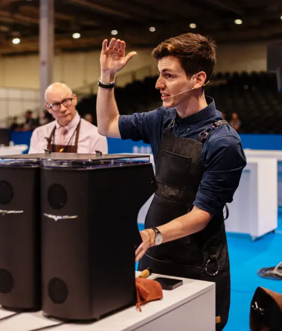 Daniele Ricci speaks to competition judges from behind an espresso grinder.