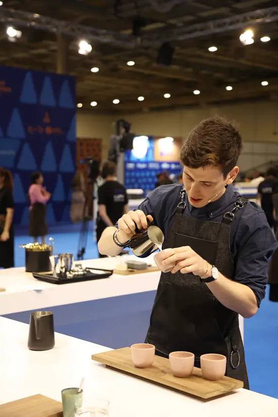 Daniele Riccio pours lattes into ceramic cups at the World Barista Championship.