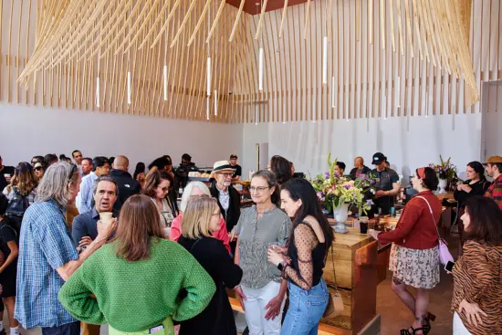 Under a large wooden sculpture on the ceiling, guests mingle with drinks and talk to Laura.