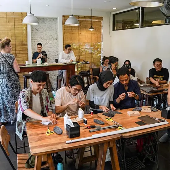 People sit together at tables crafting with old coffee packaging.