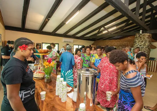 A large group of people try out coffee at a long table.