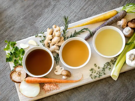 A platter with three different color broths and vegetables.