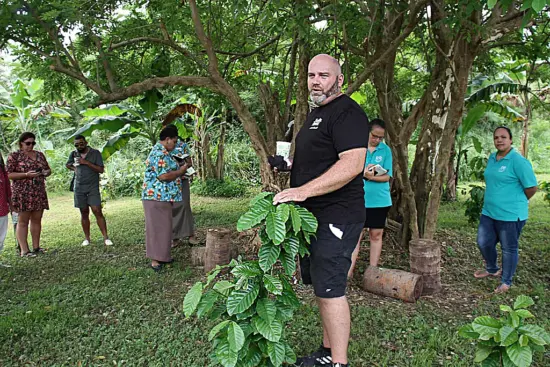 Luke holds coffee branches while he speaks to visiting group.