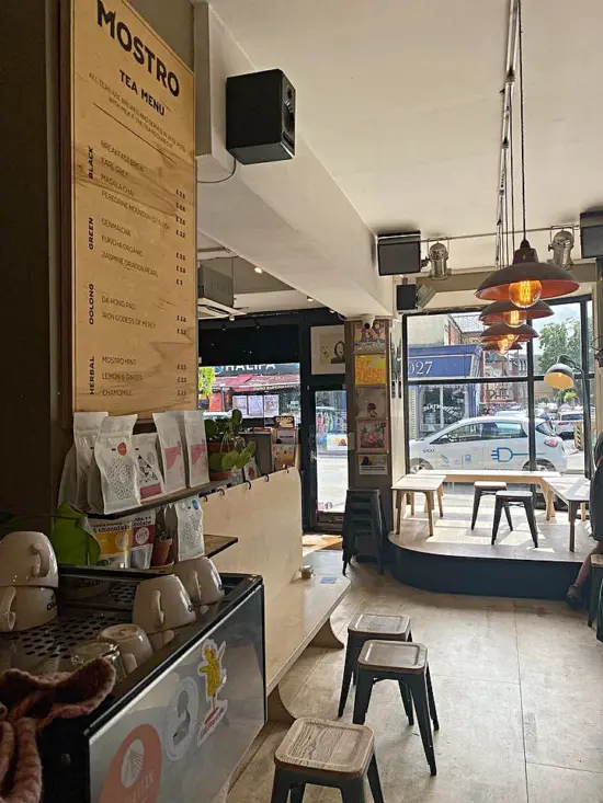 The menu and espresso machine at Mostro, with seating by the front window and vinyl records decorating the wall.