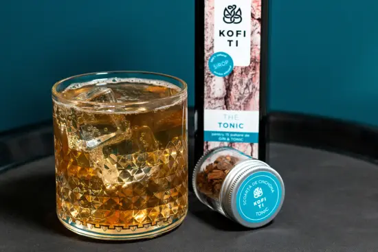 A glass of Kofi Ti tonic, with the tonic water branded glass bottle.