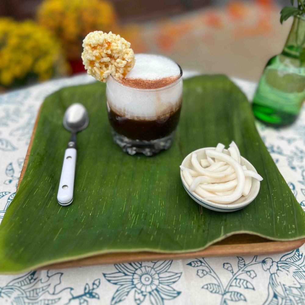 The Anuk Magsaya hot cocoa in a glass on a green placemat.