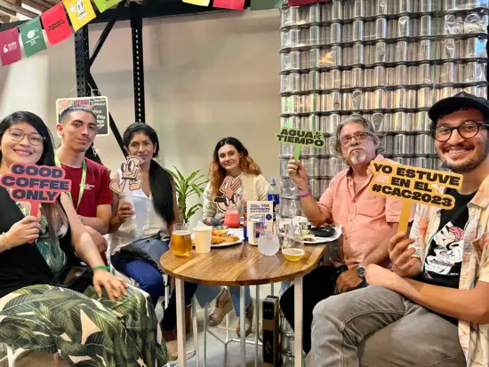 a group of men and women hold up small signs and sit at a table.