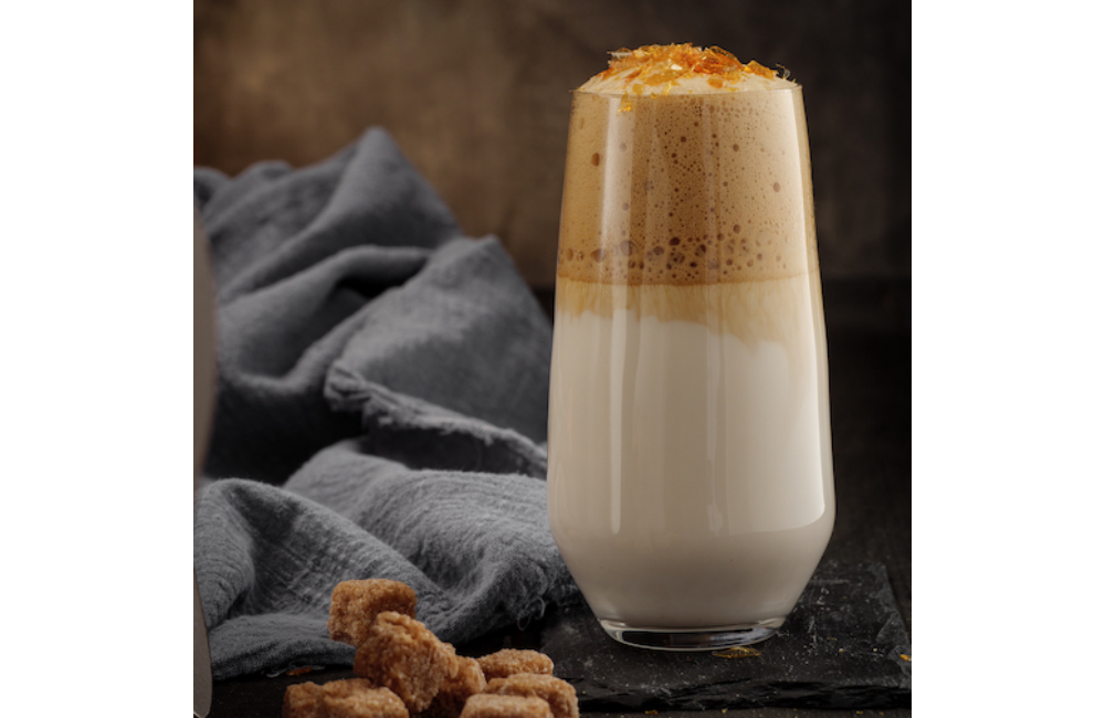 A signature drink called Portland Maple Bar Oat Latte in a tall glass with ice.