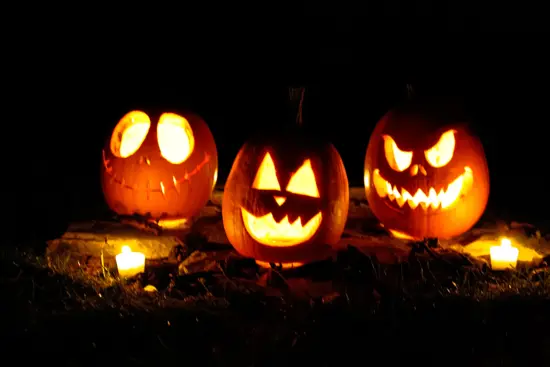 Three carved smiling jack-o-lanterns with candles inside.