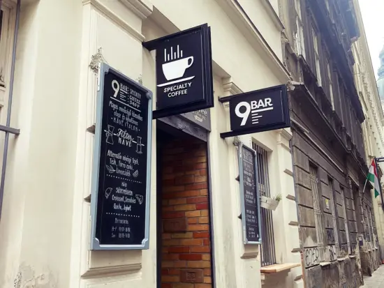 The exterior of 9 Bar has blackboard signs with drink menus and a brick entryway.