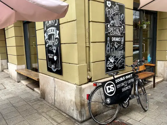 Double Shot's storefront has neat wooden benches and a bicycle with a fabric store sign.