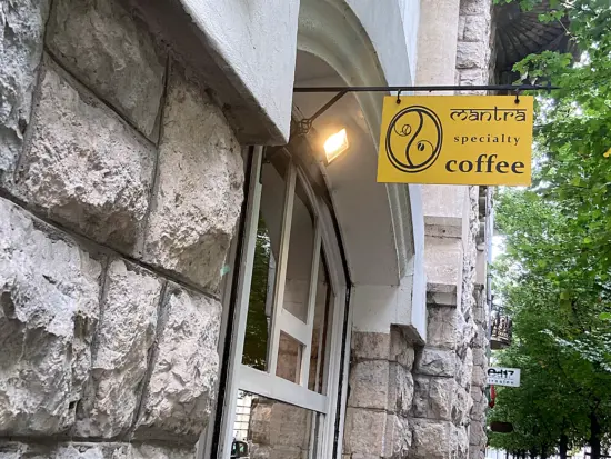 Mantra's sign hangs over the side of a stone building above an arched window.