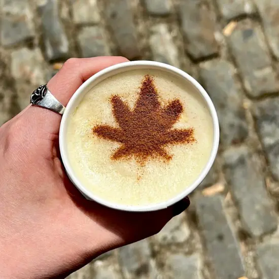 A latte with a cannabis leaf design on the milk.
