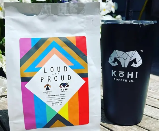 An inclusive rainbow pride flag on a coffee bag, the Loud and Proud blend from Kohi Coffee Co, next to a black mug branded with Kohi logo in white.