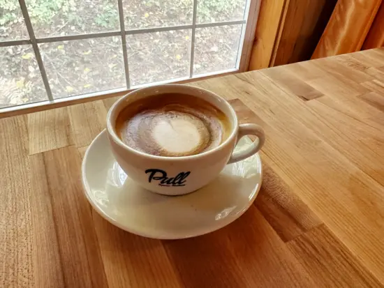 A latte mug and saucer with Pull logo on the side.