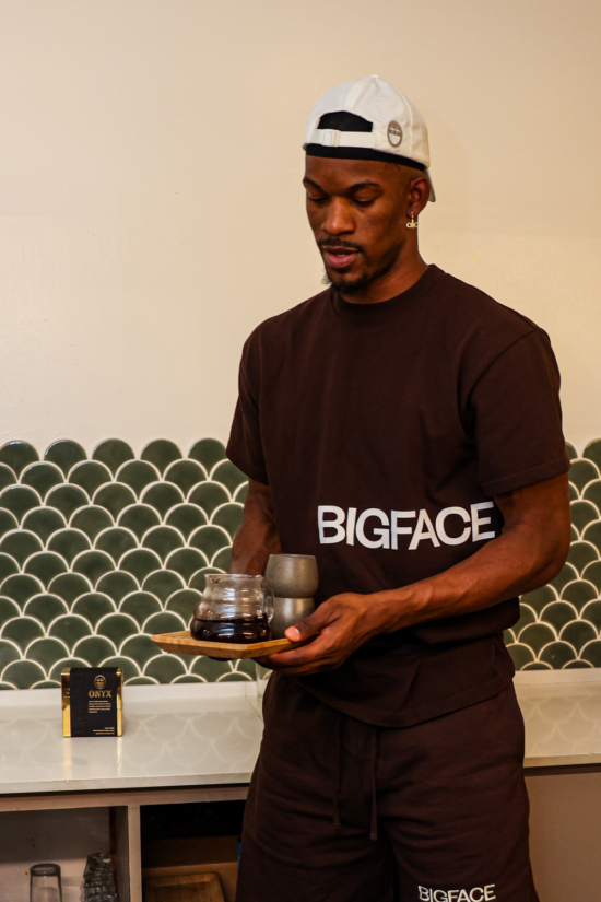 Jimmy Butler wears a BIGFACE hat and T-shirt, carrying a pourover carafe of coffee and two cups.