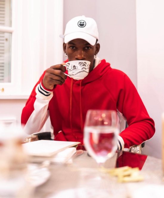 Jimmy drinks coffee at a table from a ceramic cup.