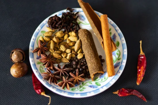 A platter of raw spices: cardamom pods, star anise, cinnamon bark, chilis, and more.