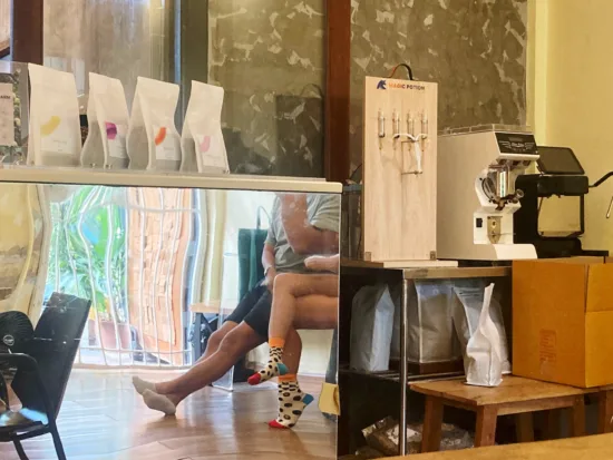 People's colorful socks are reflected from the back of an espresso machine.