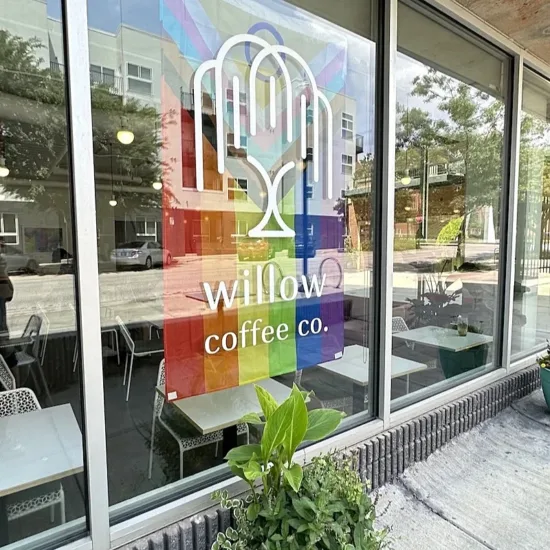 In the window of Willow Coffee Co, a pride flag hangs above the cafe tables inside.