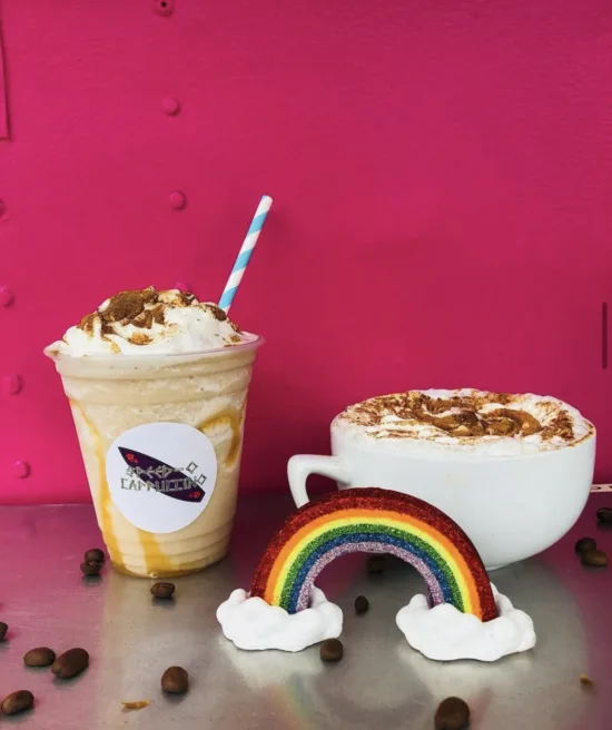 A glittery rainbow with clouds adorns the display of an iced latte and hot coffee drink at Speed-O.
