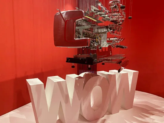 The disassembled parts of an m100 are suspended from the ceiling above a giant WOW.