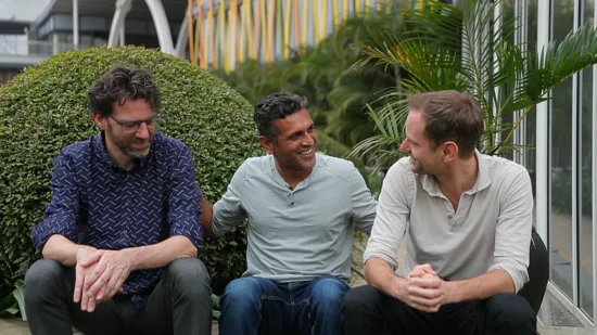 Three men from Ethos sit together outside a building.