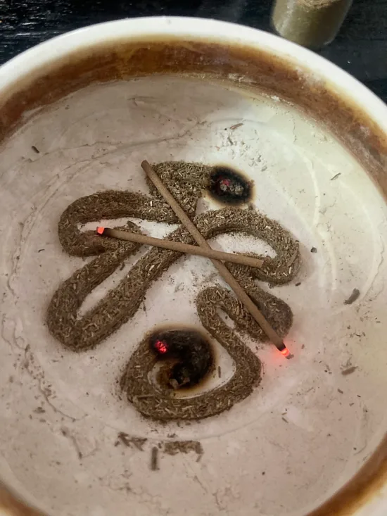 A swirl of incense wood in a clay bowl.