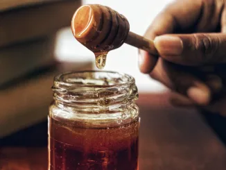 A jar of honey with a honey spoon.